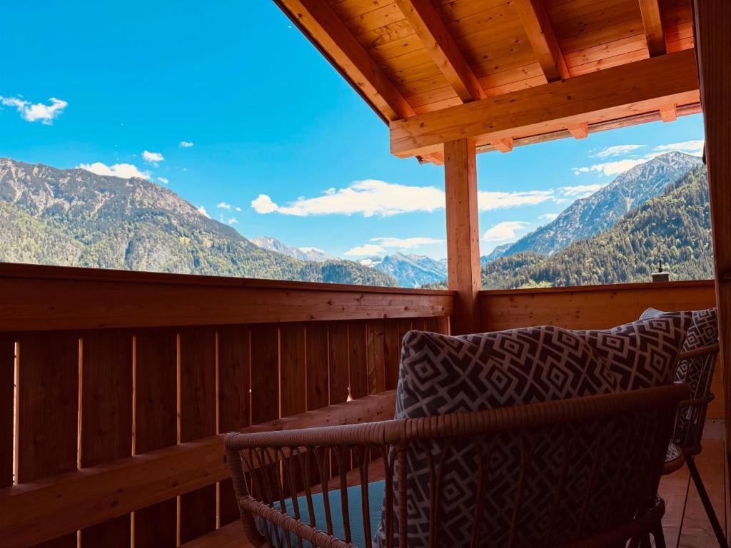 a porch with a chair and a view of mountains at Ferienwohnungen Göhl in Bad Hindelang