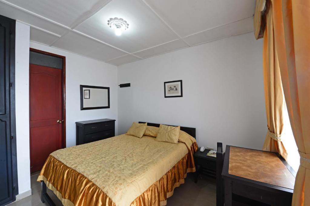 una camera con un letto e una porta rossa di Hotel Popayan Plaza a Popayan