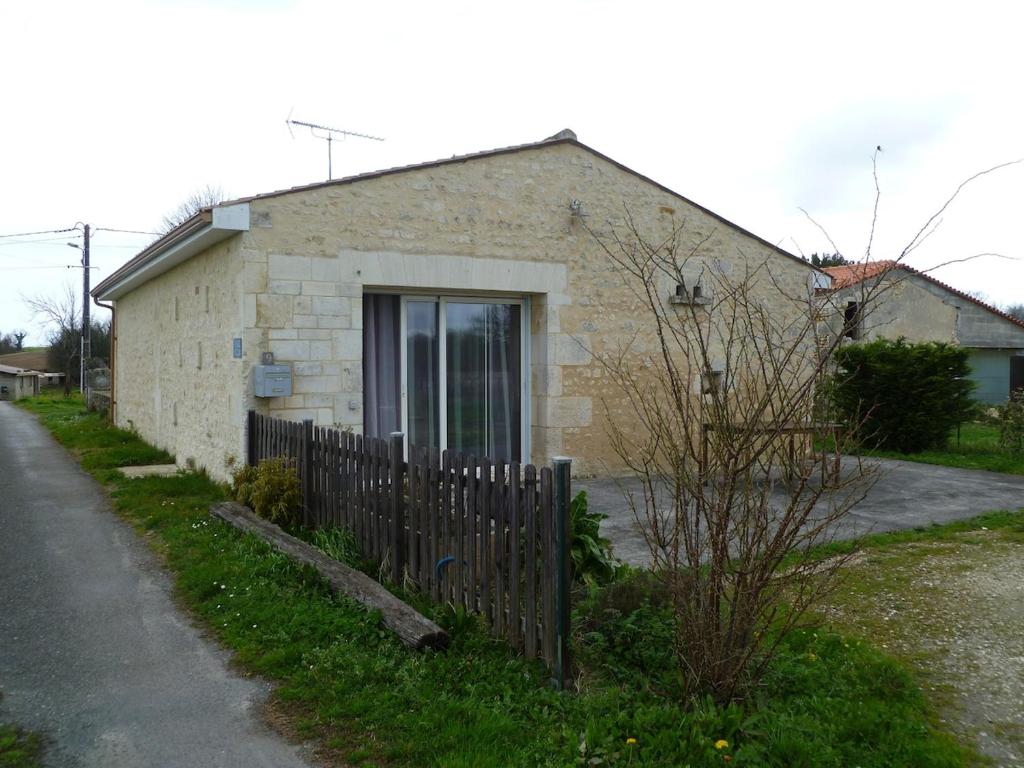 een stenen huis met een hek ervoor bij La grange in Saint-Germain-de-Lusignan