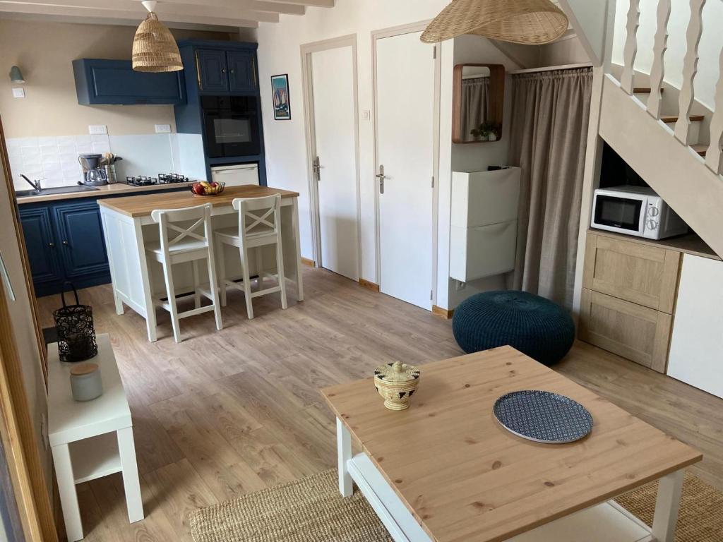 un salon avec une table et une cuisine dans l'établissement Charmante maison proche de la mer à Locquémeau, à Locquémeau