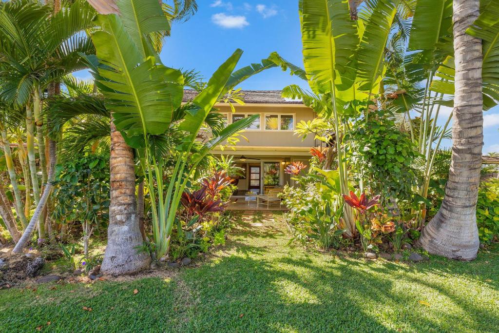 una casa con palmeras delante en Puamana 87-2 Premium Garden View, en Lahaina