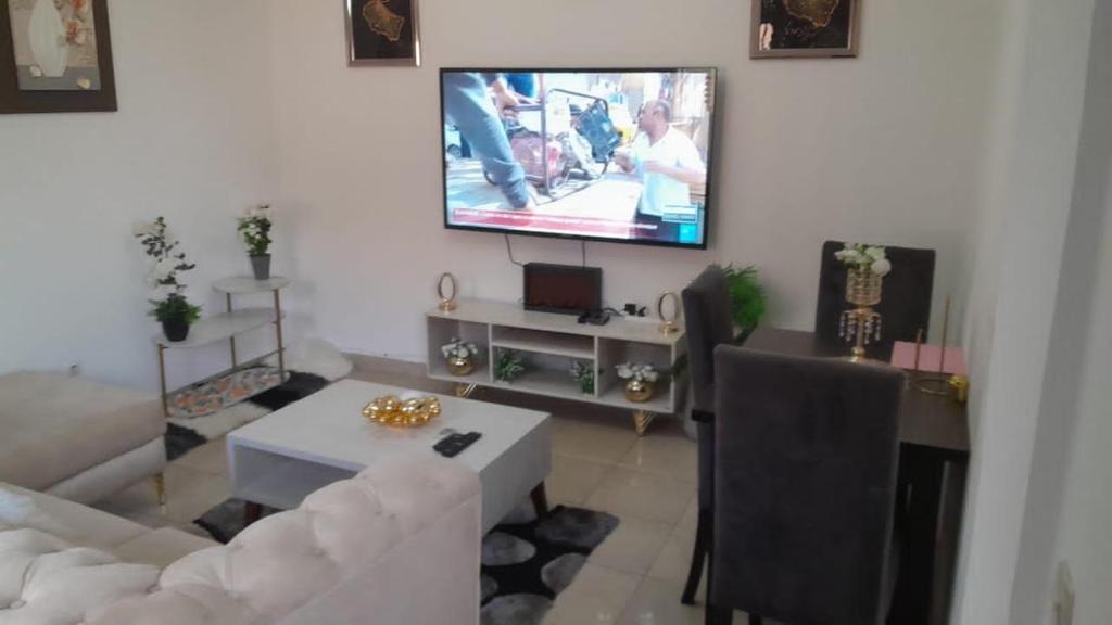 a living room with a white couch and a tv at PASCAL meublés in Yaoundé
