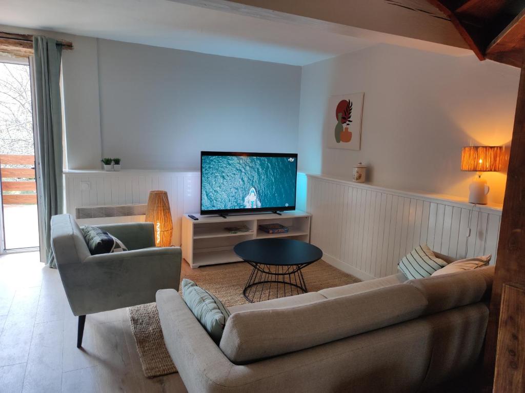 un salon avec un canapé et une télévision dans l'établissement Gitesdanslelot, à Concorès