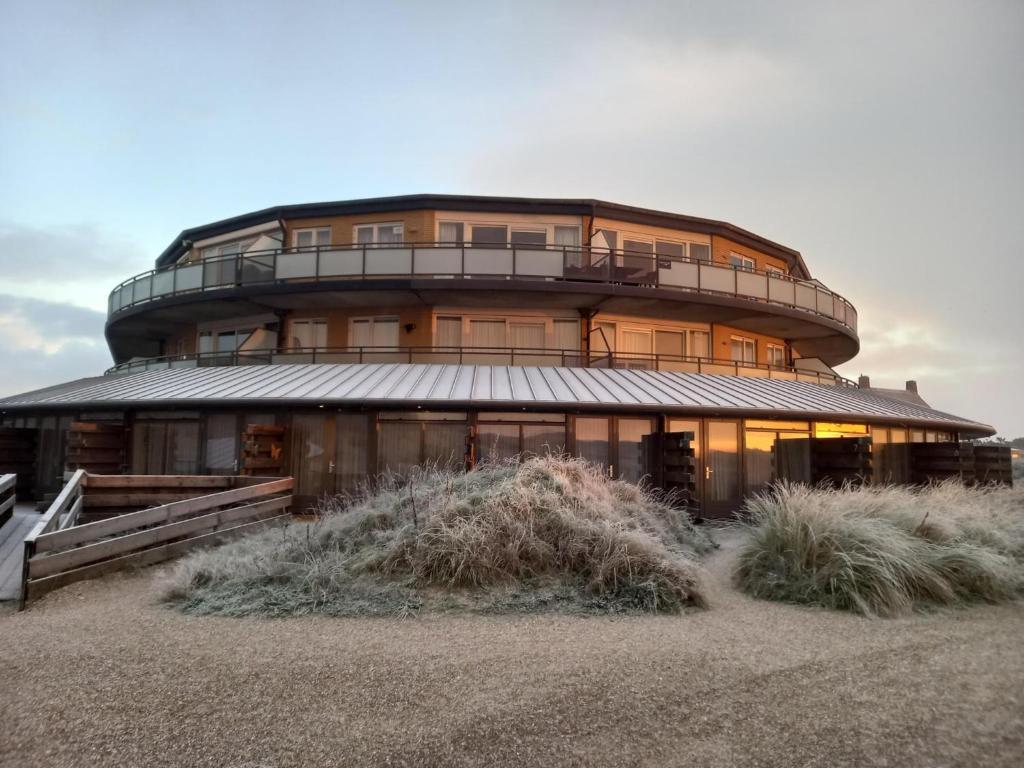 a large building on the beach with tall grass at Seaside Double Duyn Suites in Callantsoog
