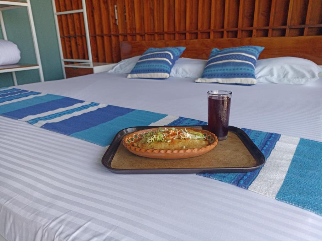 a tray with a pizza and a drink on a bed at Hotel Momotus Tuxtla - Desayuno opcional in Tuxtla Gutiérrez