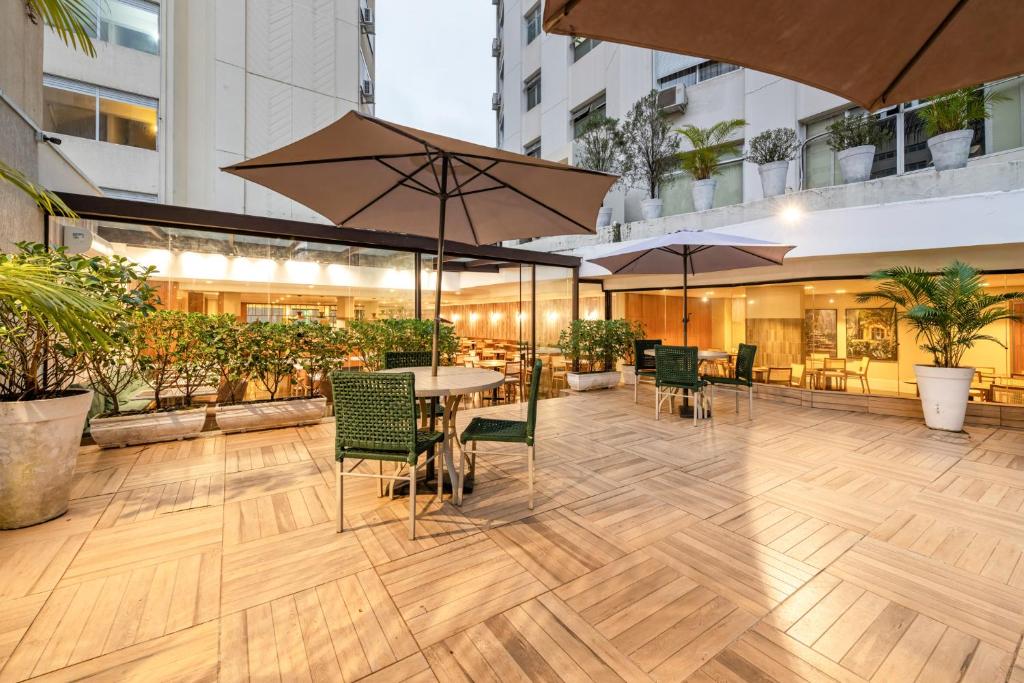 a patio with a table and chairs and umbrellas at Hotel Trianon Paulista in Sao Paulo