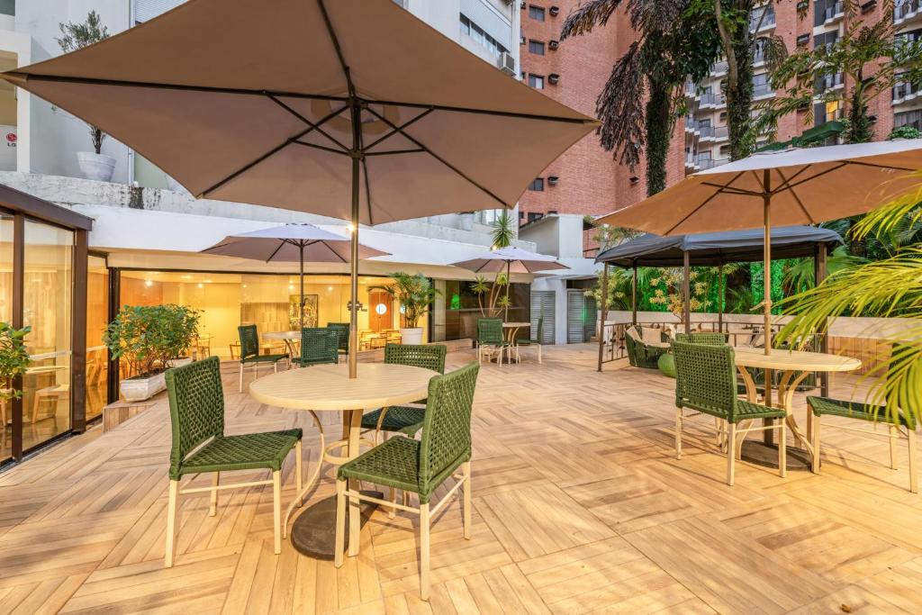 a patio with tables and chairs and umbrellas at Hotel Trianon Paulista in Sao Paulo