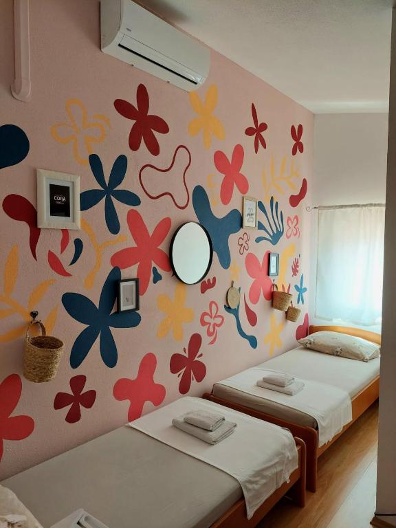 two beds in a room with flowers on the wall at Guest House Sandra in Tisno