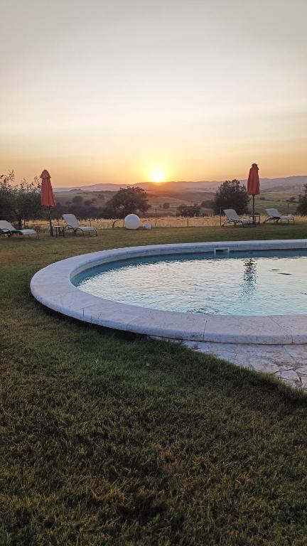 a swimming pool with the sunset in the background at Bio Agriturismo La Bell'Antiglia in Montemerano
