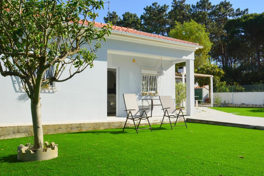 a white house with chairs and a tree in the yard at Paradise in Lagoa by DolceStay in Sesimbra