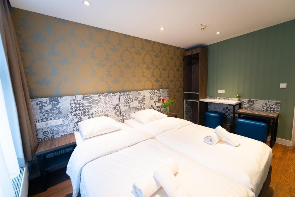 een slaapkamer met 2 bedden en witte lakens bij The Old Nickel Hotel in Amsterdam