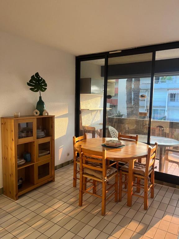 une salle à manger avec une table et des chaises et une fenêtre dans l'établissement Studio cabine - Grau du Roi, au Grau-du-Roi
