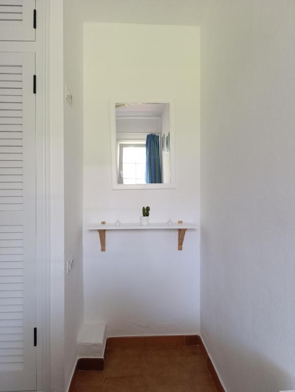 a white bathroom with a sink and a window at Apartamento Ideal in Alaior