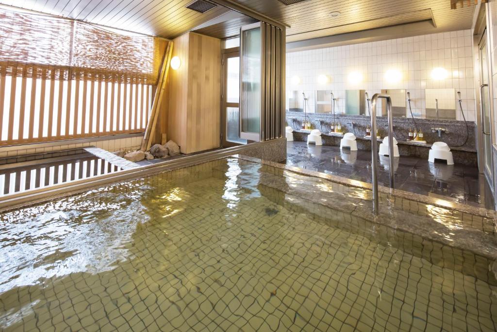 a large pool of water in a bathroom with sinks at HOTEL MYSTAYS Kanazawa Castle in Kanazawa