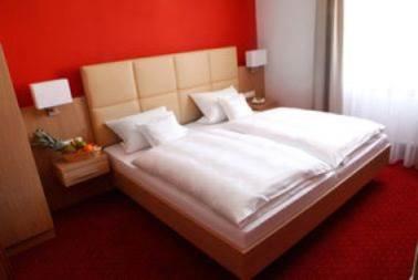 1 dormitorio con cama blanca y pared roja en Hotel-Gasthof-Kohlmeier, en Kranzberg