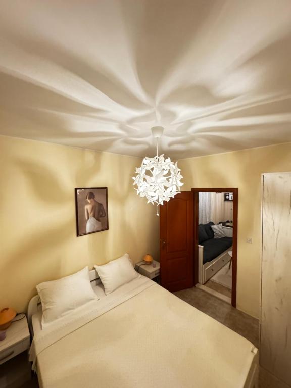 een slaapkamer met een bed en een kroonluchter bij Apartman Petar - Portonovi Đenovići in Ðenovići