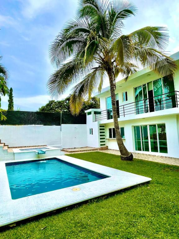 a palm tree and a swimming pool in front of a house at Quinta Colinas Oaxtepec in Oaxtepec