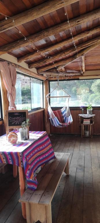 ein Zimmer mit einem Tisch und einer Hängematte in einer Hütte in der Unterkunft Cabaña rodeada de naturaleza en Ollantaytambo in Ollantaytambo