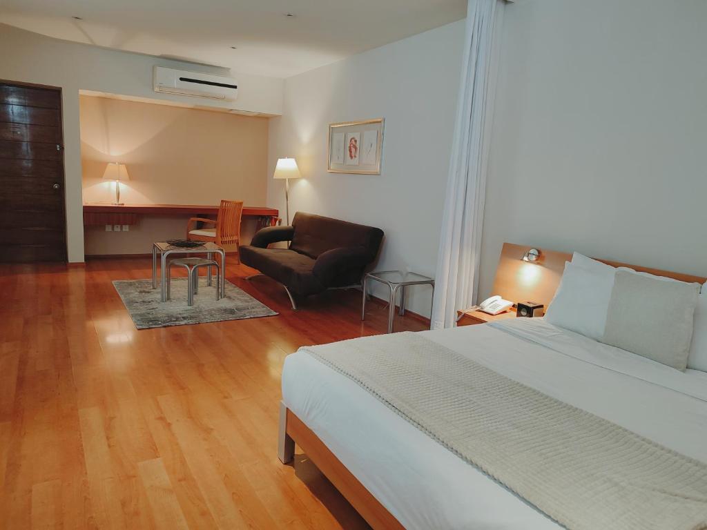 a bedroom with a bed and a couch and a chair at Lombardo Suites in Mexico City
