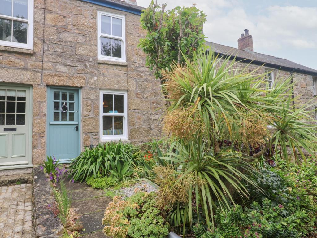 a stone house with a blue door and plants at 2 The Cottages in Ludgvan