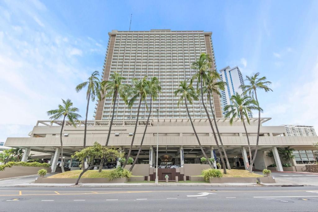 Un edificio alto con palmeras delante. en Ala Moana Condo, en Honolulu