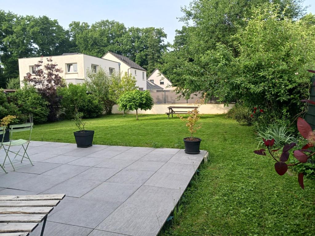 a garden with a patio with plants in the grass at Chambre calme à la limite de Belfort, maison avec jardin proche du stade, du skatepark et de la rivière in Offemont