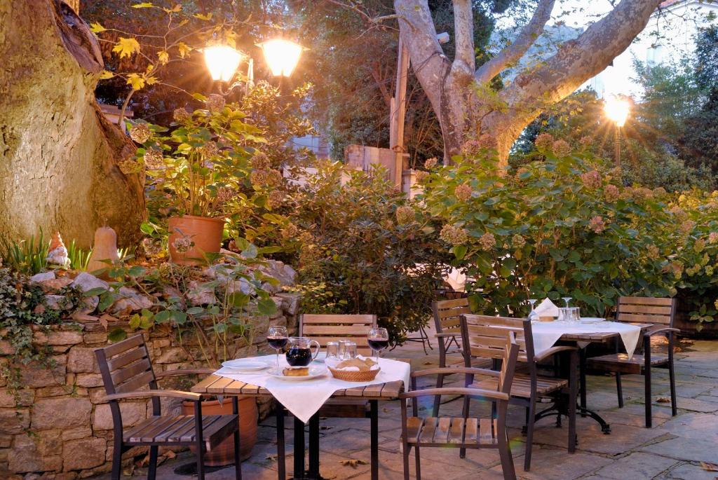 a patio with tables and chairs in a garden at Gastronomy Hotel Kritsa in Portaria