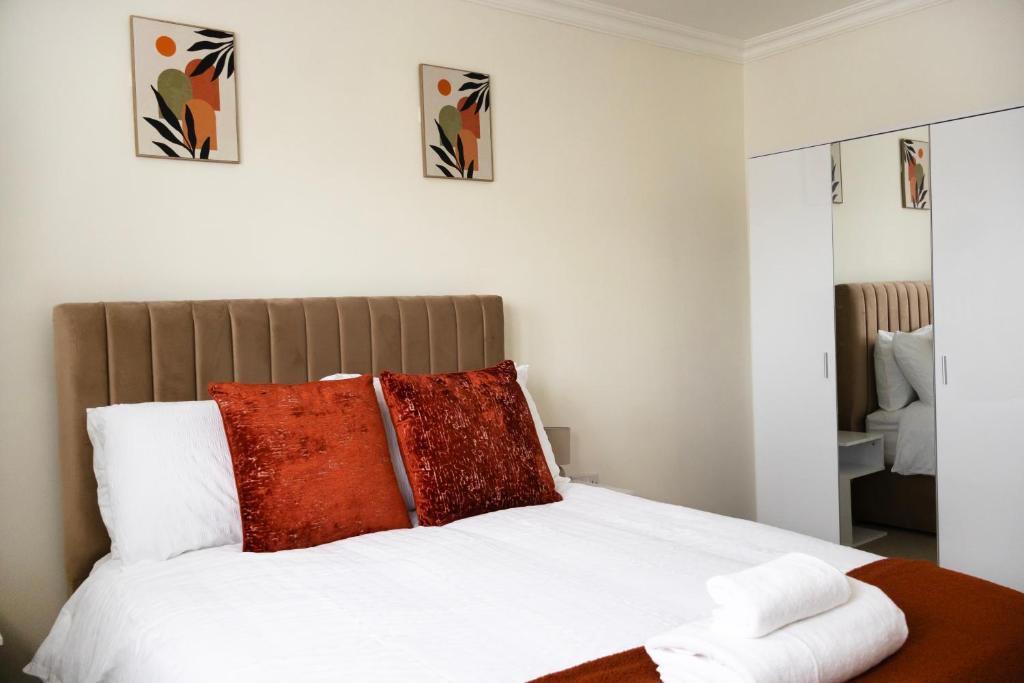 a bedroom with a white bed with red pillows at Home away from Home in Aveley