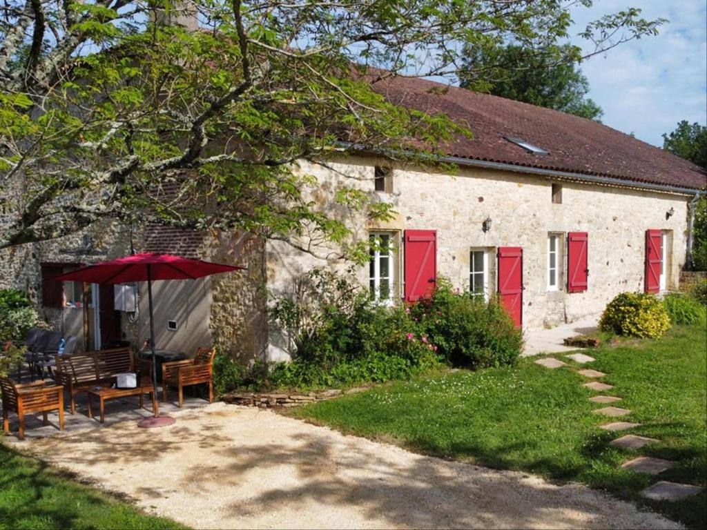 une maison avec des portes rouges, une table et un parapluie dans l'établissement Ferme Saint Martin le Redon, à Soturac