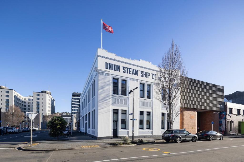 a white building with a flag on top of it at Handy Inner City Apartment in Dunedin