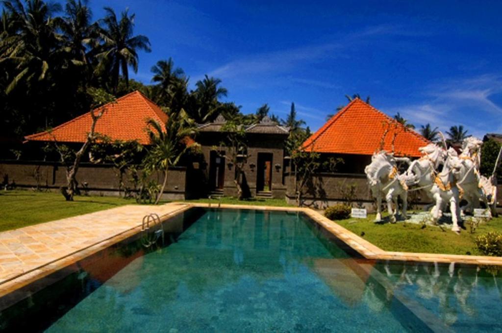 a house with a swimming pool with a statue of horses at Puri Rai Hotel in Padangbai