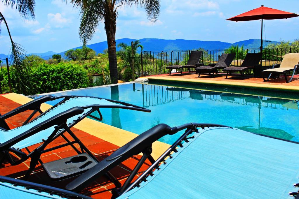 a swimming pool with chairs and an umbrella at Wellness Center El Secreto in Tepoztlán