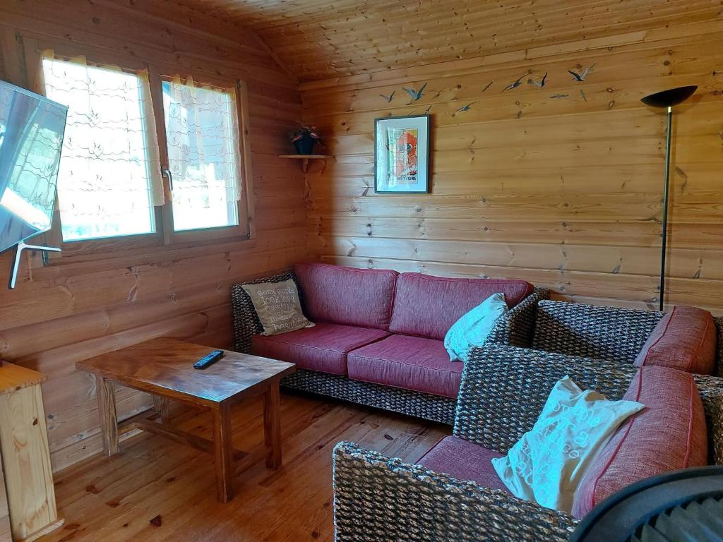 un salon avec un canapé rouge et une table dans l'établissement Chalet in Vosges near Ski Slopes, cleaning included, à Saint-Maurice-sur-Moselle