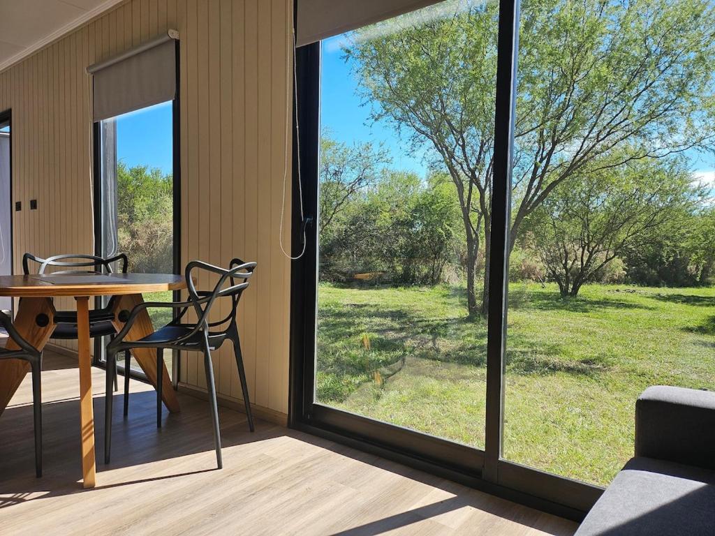 a room with a table and chairs and a large window at La Recompensa Tiny in Colonia Nuevo Paysandú