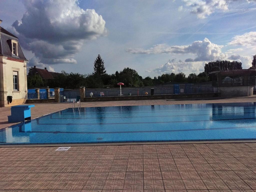 une grande piscine bleue avec un ciel nuageux en arrière-plan dans l'établissement Farmhouse in Giroux near Forest & Lake, cleaning included, à Giroux