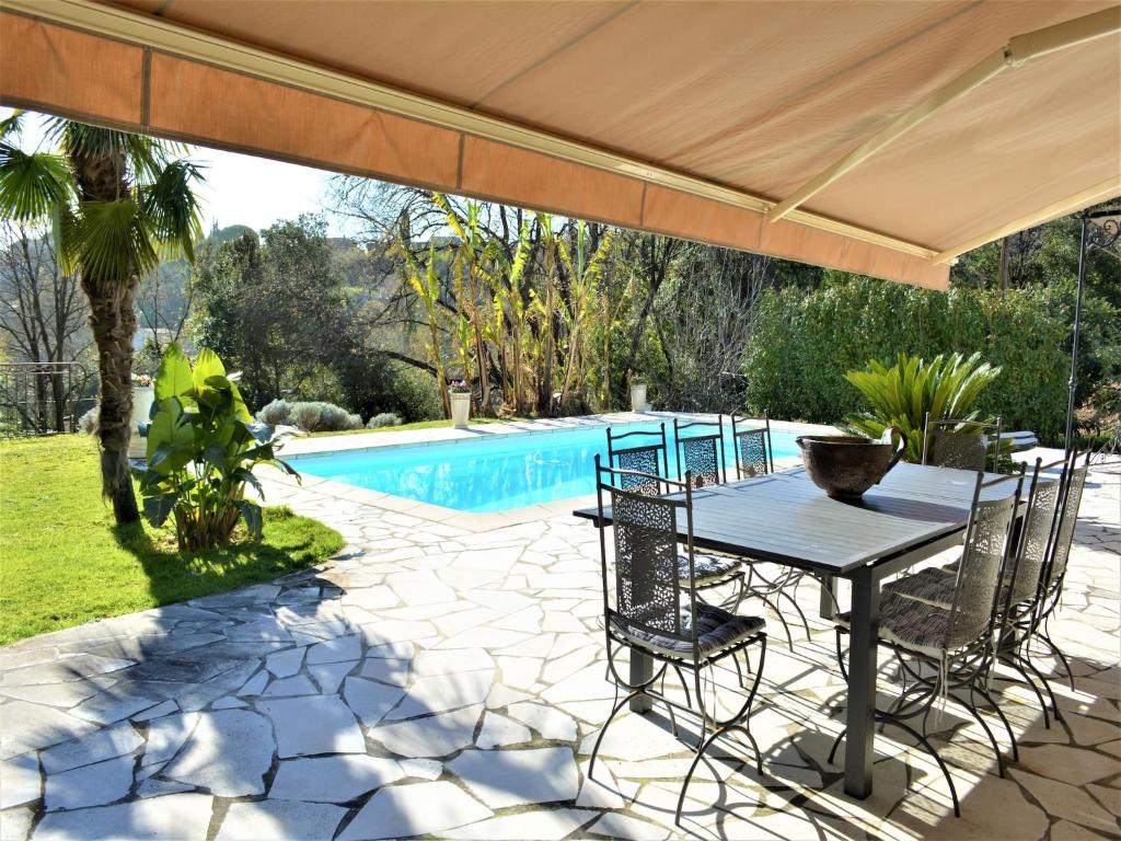 un patio avec une table et des chaises à côté d'une piscine dans l'établissement Villa in Saint Paul with Pool & Garden, cleaning included, à Saint-Paul-de-Vence