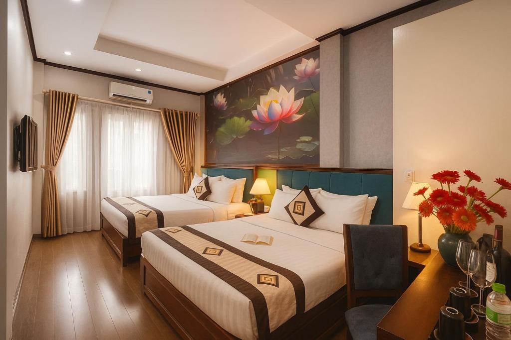Una habitación de hotel con dos camas y un escritorio. en Hanoi Sena Hotel & Travel, en Hanói