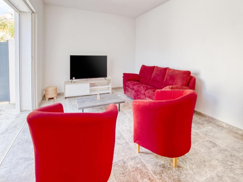 Il comprend un salon doté de fauteuils rouges et d'une télévision. dans l'établissement Holiday Home La Seyne near Beaches, cleaning included, à La Seyne-sur-Mer