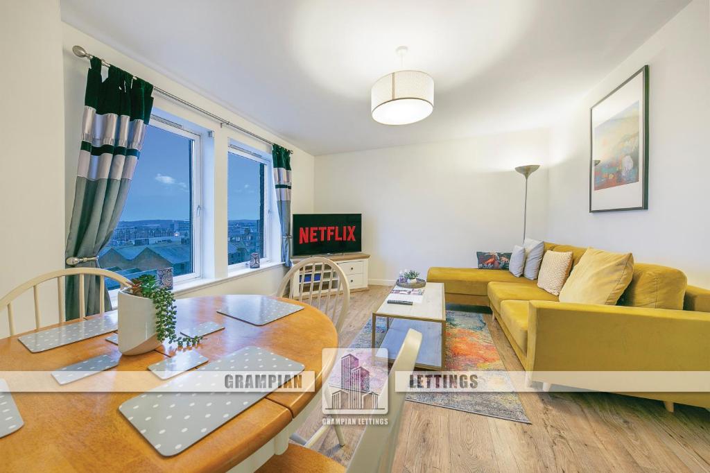 a living room with a yellow couch and a table at Castle Terrace - Grampian Lettings Ltd in Aberdeen