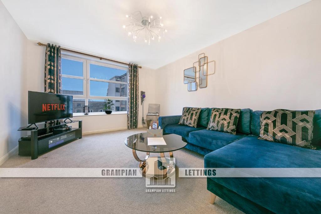 a living room with a blue couch and a tv at Kings Lodge - Grampian Lettings Ltd in Aberdeen