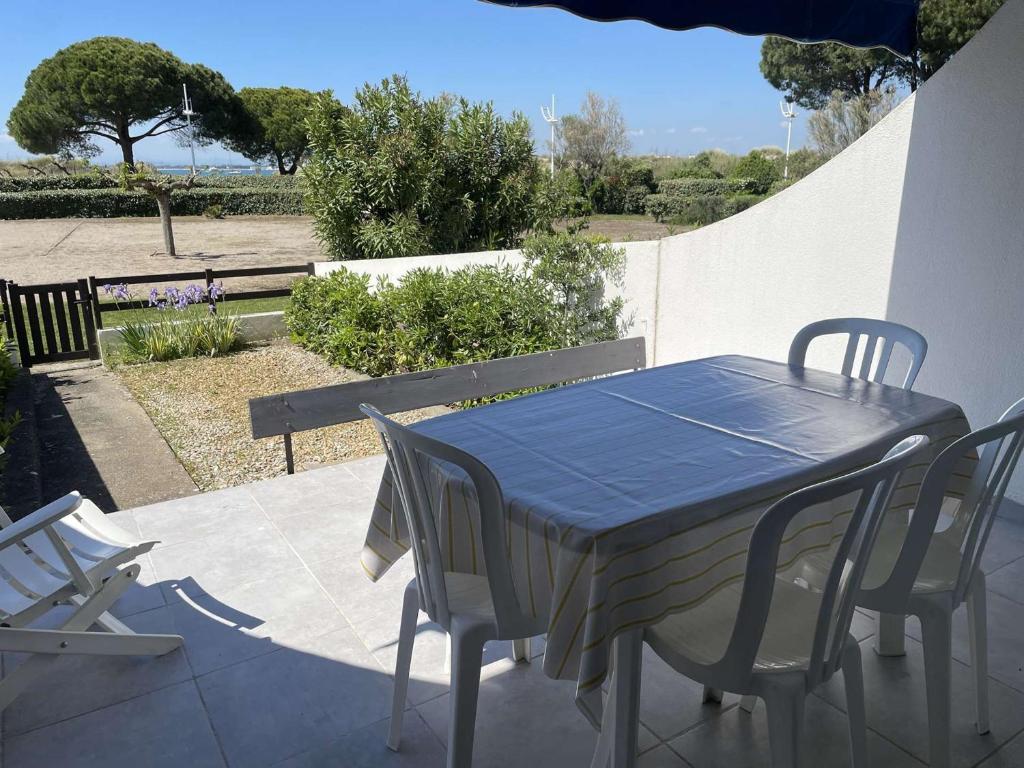 une table et des chaises bleues sur une terrasse dans l'établissement Studio + 2 cabines direct plage, terrasse, parking, 4 pers. - FR-1-731-142, au Grau-du-Roi