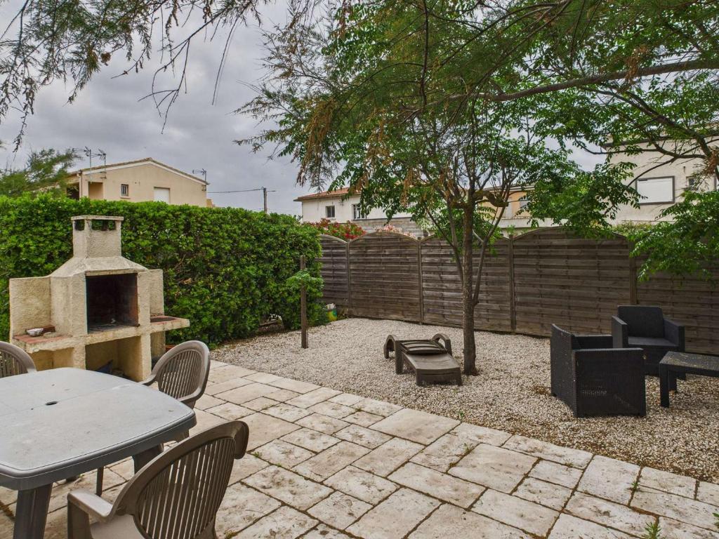 un patio avec une table, des chaises et un barbecue dans l'établissement Maison plain-pied 3 chambres, terrasse et climatisation, 8 pers - FR-1-326-860, à Marseillan