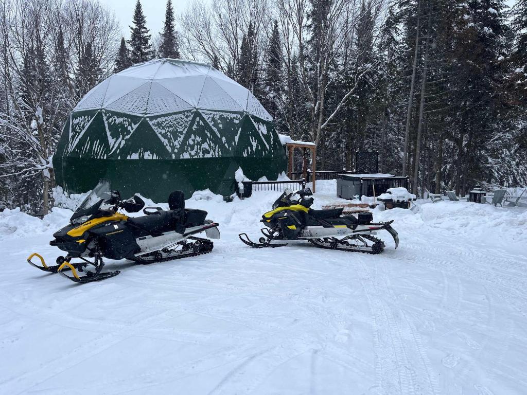 two snow motorcycles parked in the snow in front of a tent at Les Domes de la Riviere Alick SPA et Riviere in Saint-Paul-de-Montminy