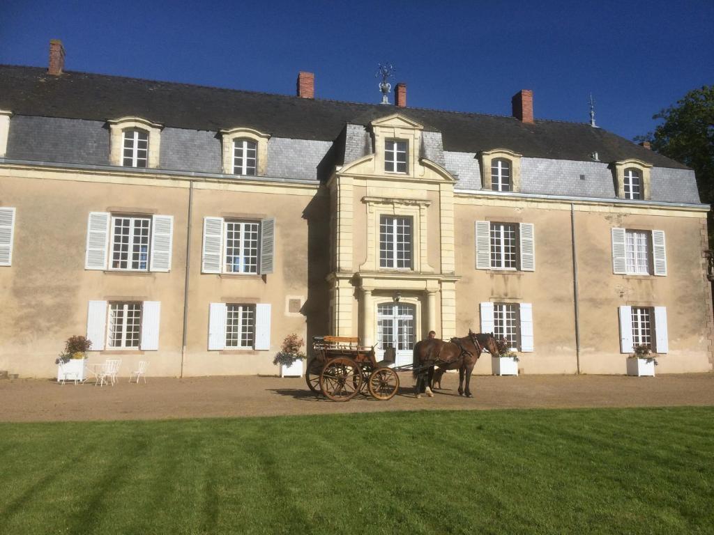 une calèche tirée par des chevaux devant un grand bâtiment dans l'établissement Chateau De Piedouault, à Jallais
