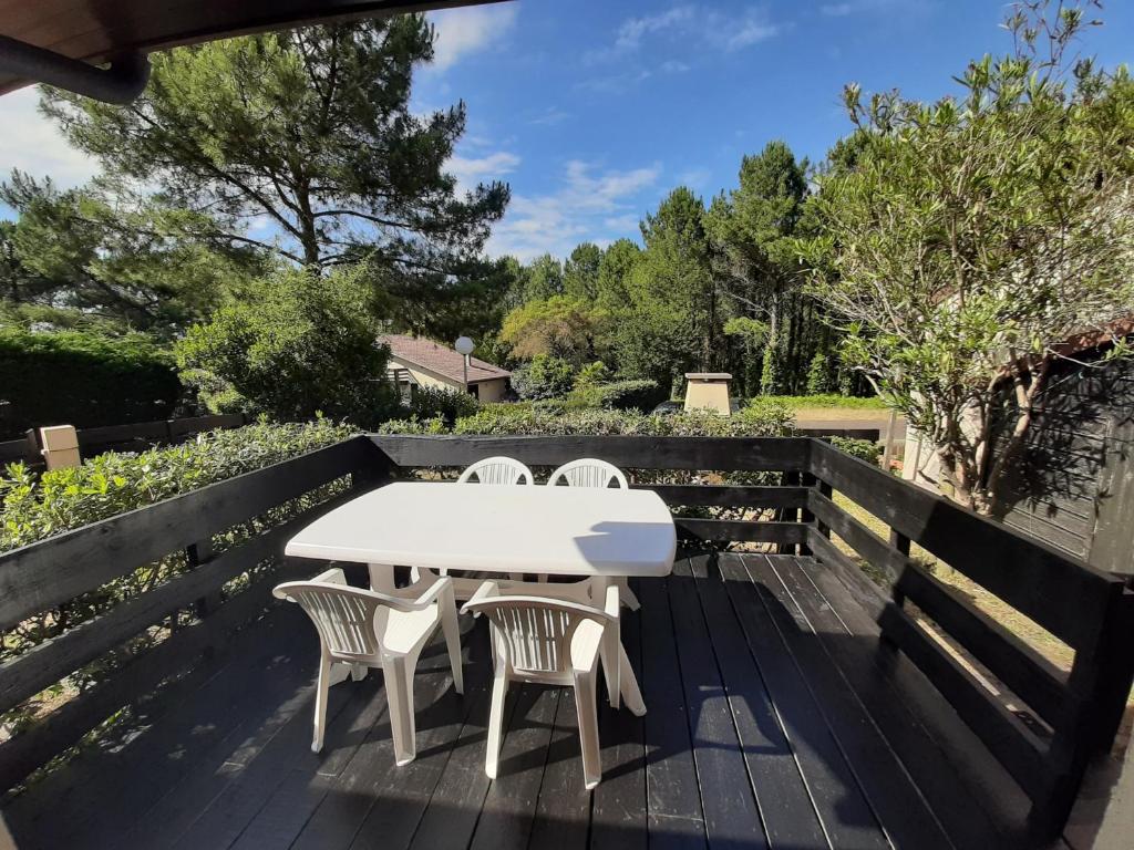 une table et des chaises blanches sur une terrasse en bois dans l'établissement Maison moderne entre forêt et océan, avec jardin et terrasse. - FR-1-239-425, à Seignosse