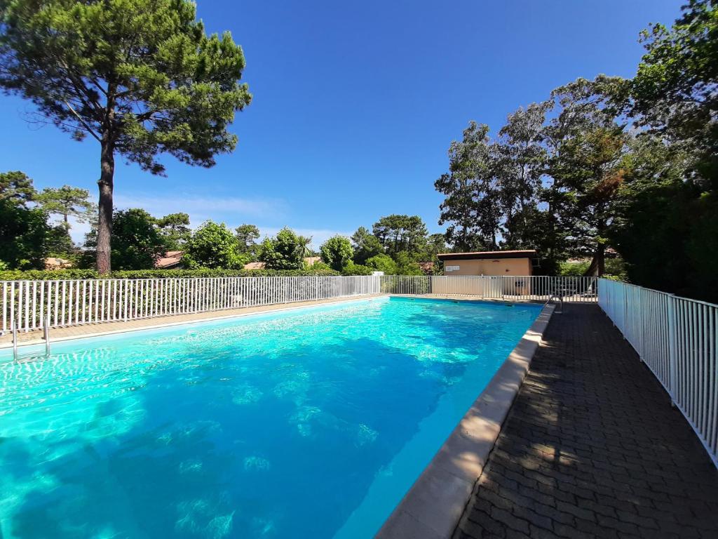 une piscine d'eau bleue et une clôture dans l'établissement Villa rénovée avec piscine, pétanque, à 2 pas des plages de Capbreton, idéale pour vacances familiales - FR-1-239-1055, à Capbreton
