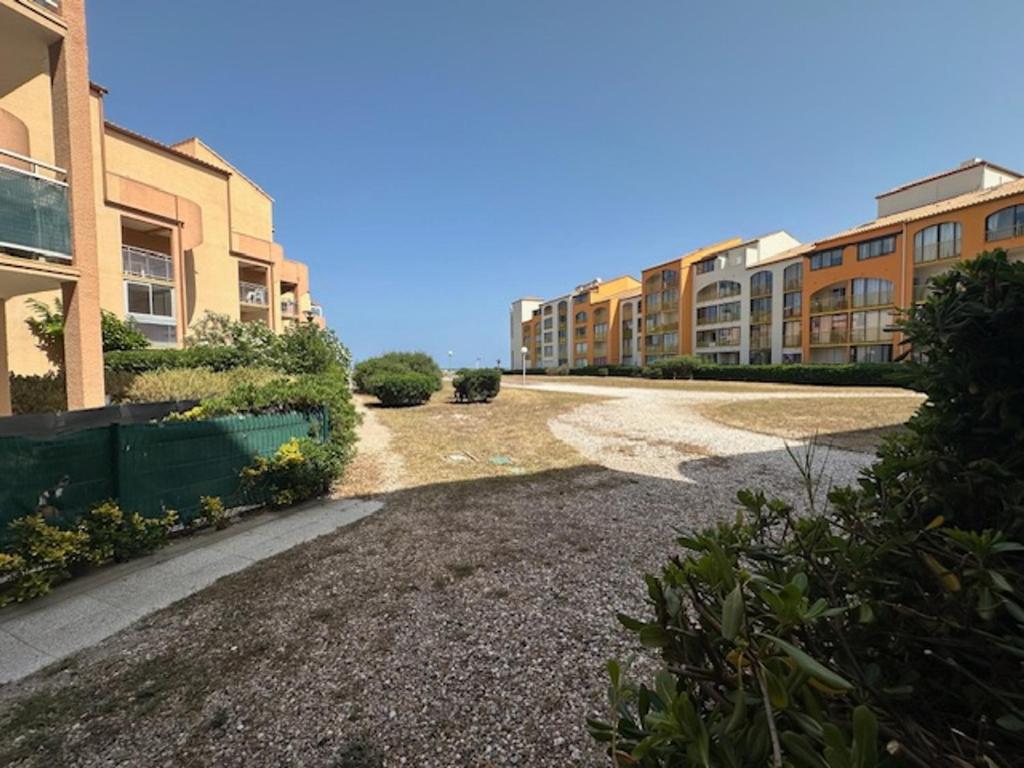 Une rue vide en face de certains immeubles d'appartements dans l'établissement Le Barcarès T2 en RDC, 4 Pers, Accès Direct Plage, Animaux OK - FR-1-799-55, au Barcarès