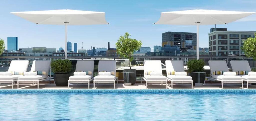 a group of lounge chairs and umbrellas next to a pool at North End 2BR Condo w Pool & Gym in Boston