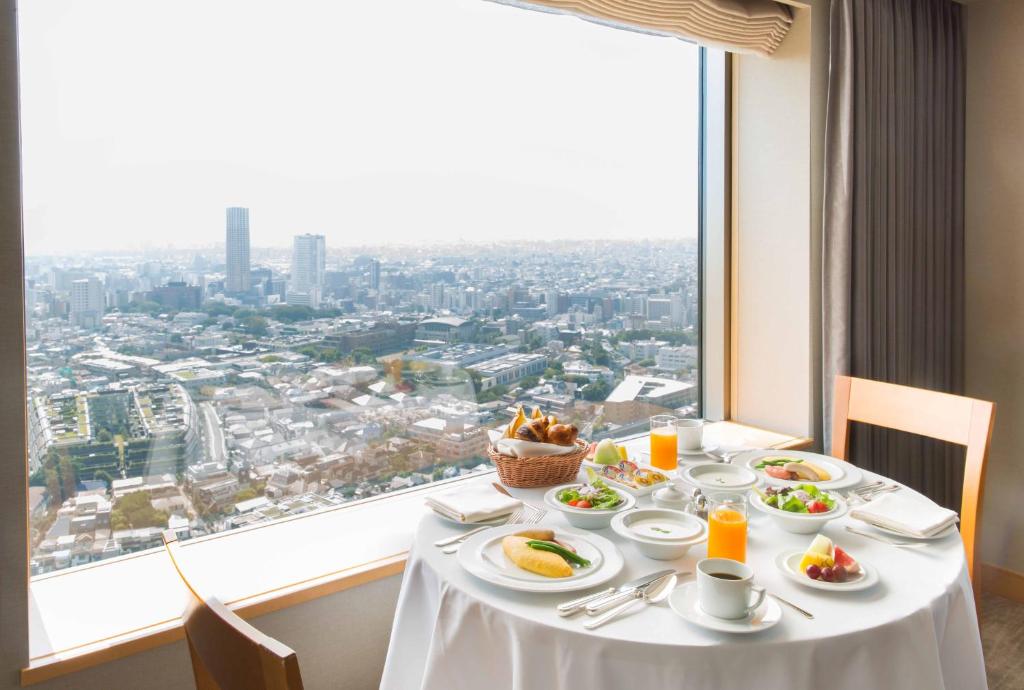 a table with plates of food and a large window at Cerulean Tower Tokyu Hotel, A Pan Pacific Partner Hotel in Tokyo