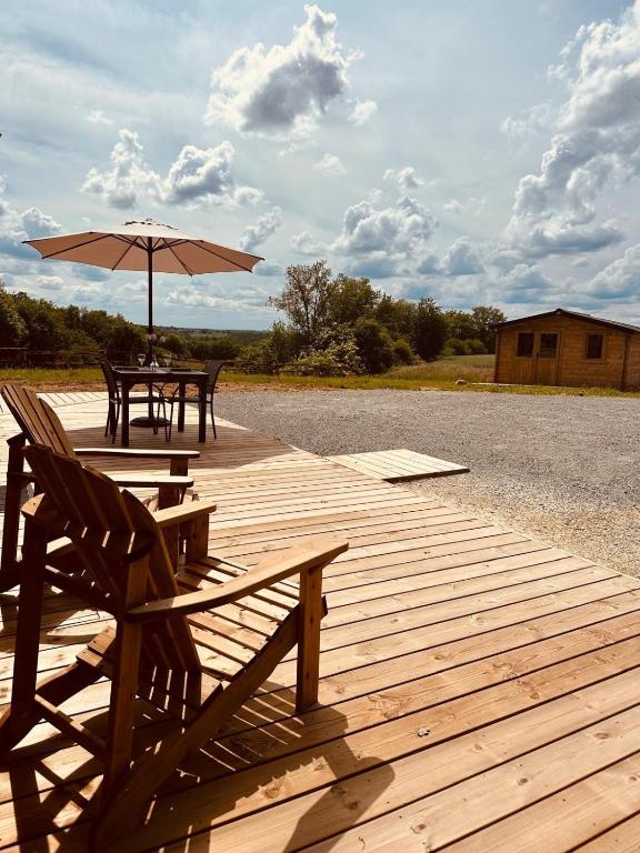 une terrasse en bois avec deux bancs et un parasol dans l'établissement la maison dans la prairie fleurie gite bleuet, à Saint-Avit-Sénieur